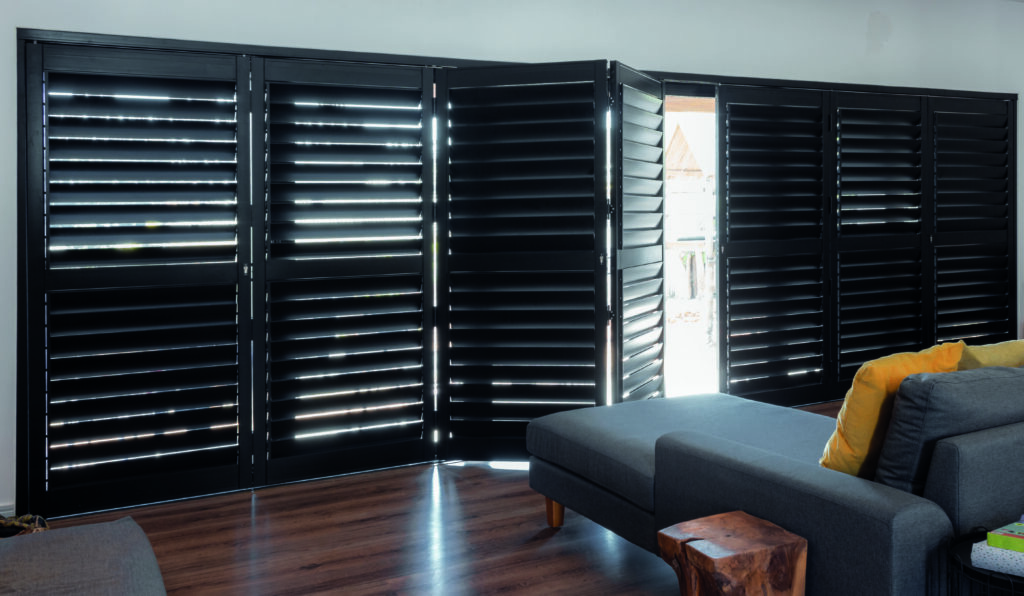 Whited-out image of l-shaped couch and semi-open dark security shutters