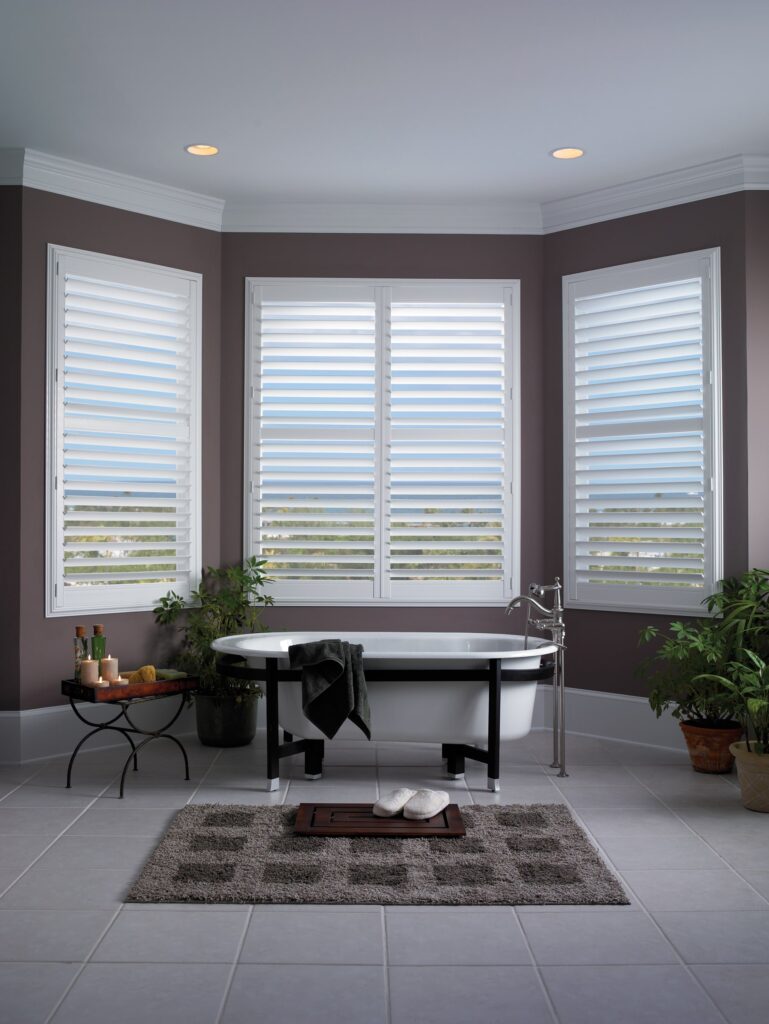 Bathroom with standing white bath, bath mat and decorations, with Vinyl Shutters.