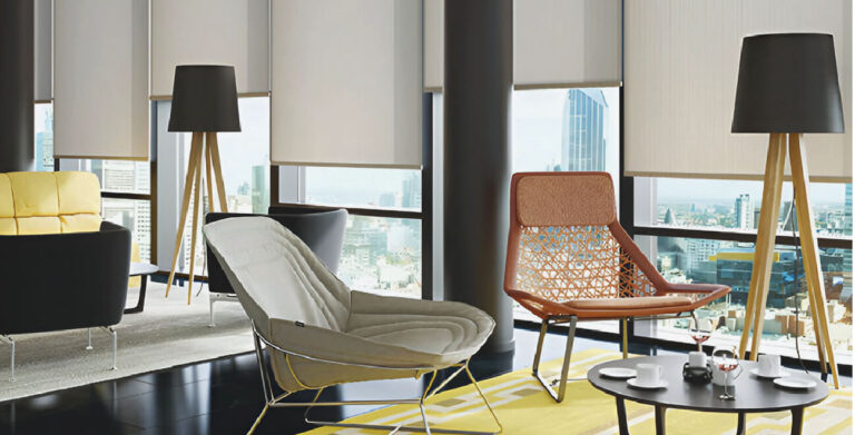 Modern chairs & decor in a tall building, with roller blinds semi-open on the windows.