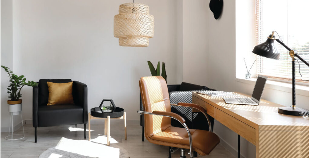 Home office with modern neutral furniture with white blinds open with sunlight showing through.